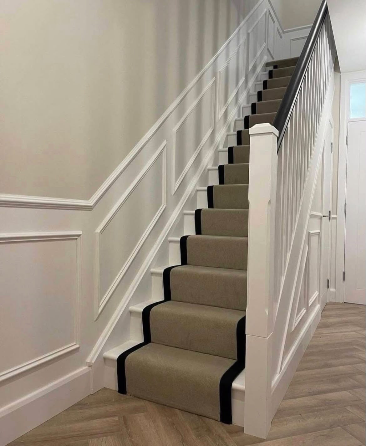 Bespoke herringbone stair runner with dark binding in a panelled hallway
