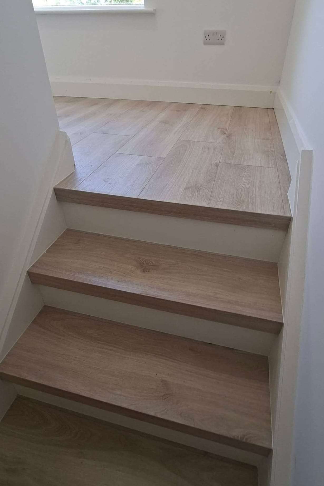 Light oak stair treads and landing in a bright stairwell