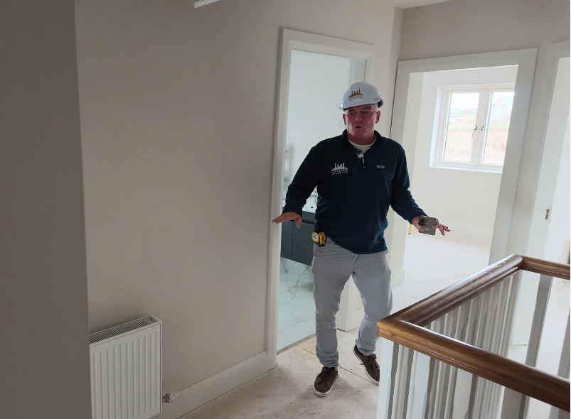 Sean from 5th Avenue Floor Store inside a new-build home under construction, wearing a site hard hat