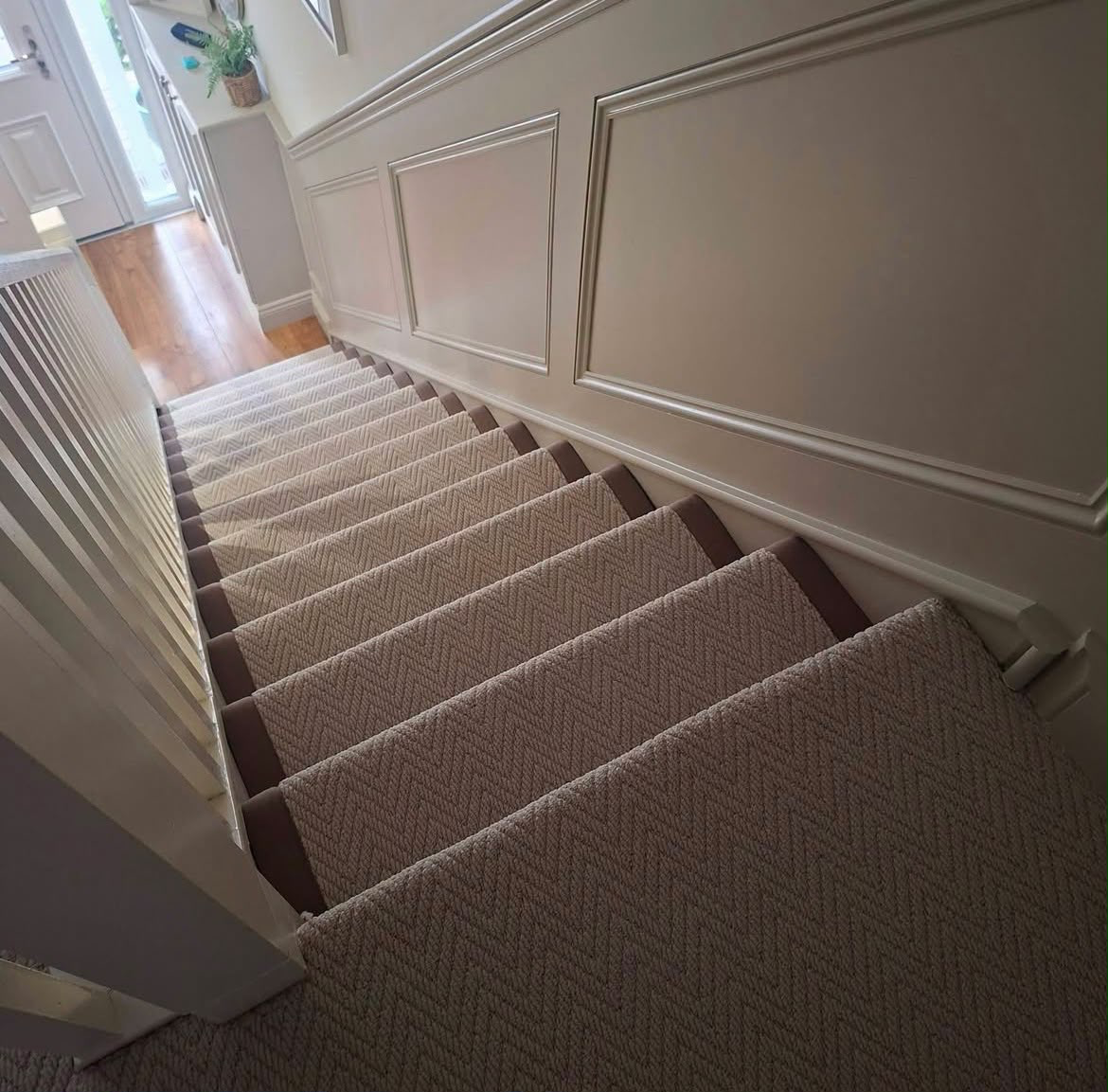 Herringbone stair runner with taupe binding in a panelled hallway